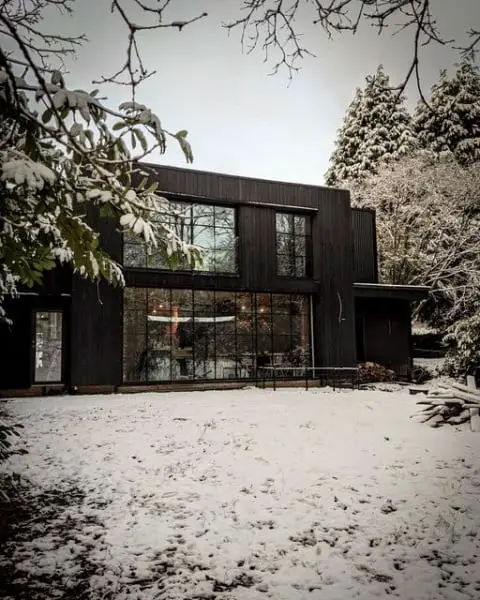 Charming And Sophisticated: A Black Modern House Design Amidst A Snowy Woodland Garden black modern home